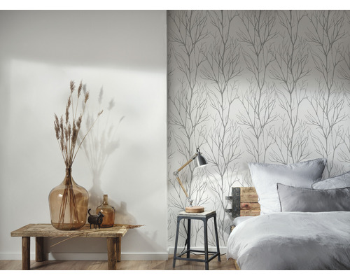 Ett sovrum med en säng, ett sängbord och en vägg med tapeter med trädtema.