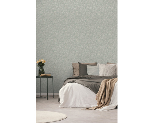 Sovrum med mönstrad tapet, säng och sidobord med blommor