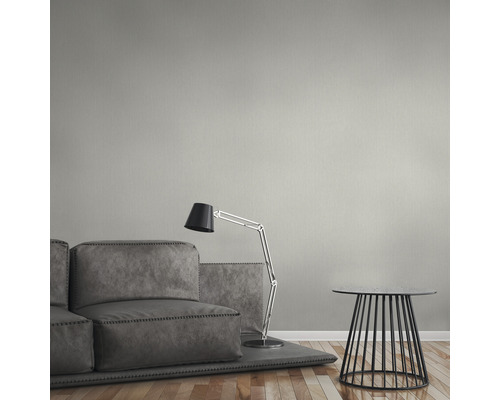 Vardagsrum med grå soffa, golvlampa och sidobord framför en enfärgad vägg