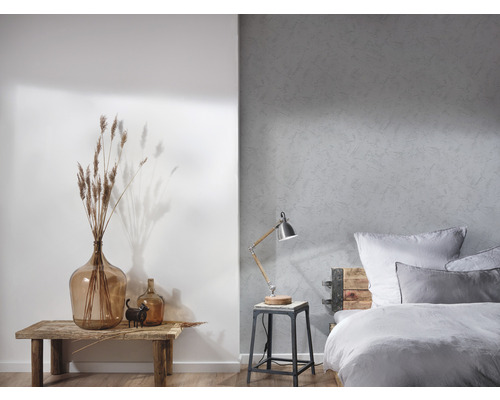 Ljust sovrum med en säng, en lampa och dekorativa element på ett träbord