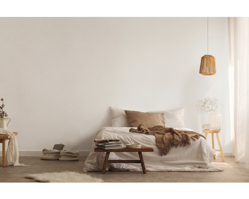 Ljust sovrum med säng, träpall och stickad lampa