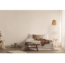 Ljust utformat sovrum med säng, träpall, lampa och dekorativa element för en vänlig atmosfär