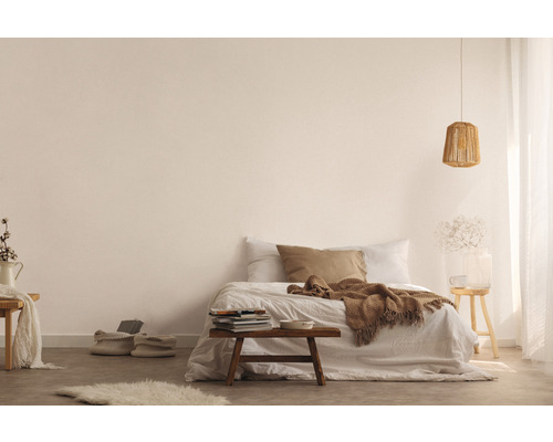 Ljust utformat sovrum med säng, träpall, lampa och dekorativa element för en vänlig atmosfär