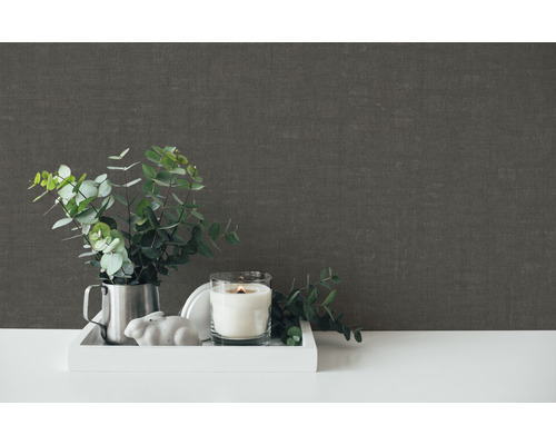 Dekorativ scen med ljus, växt och grå väggtapet