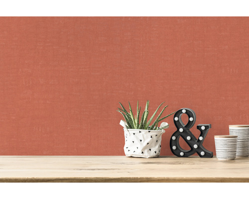 Närbild av en vägg med textilväv, krukväxt, dekorativa bokstäver och keramikmuggar på ett bord