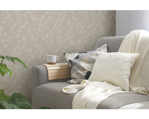 Vardagsrum med blommig tapet, soffa, kuddar och dryckeshållare