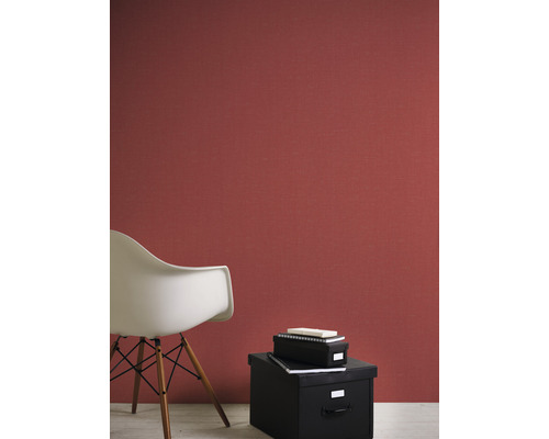 Vardagsrum med röd strukturtapet, en vit stol och svarta förvaringslådor