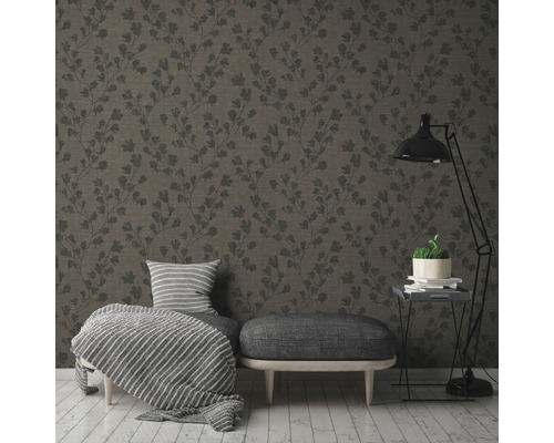 Ett vardagsrum med en mönstrad tapet, en pall, en fåtölj och en golvlampa.