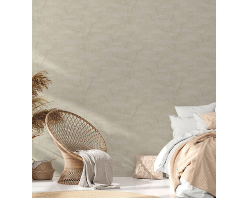 Sovrum med rottingfåtölj, säng och mönstrad tapet för en ljus, vänlig atmosfär.