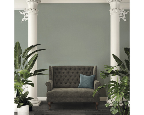 Interiörvy med soffa, kudde, pelare och växter.