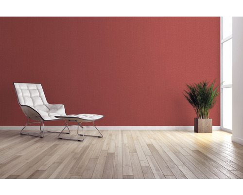 Vardagsrum med fåtölj, fotpall, krukväxt och väggdekoration