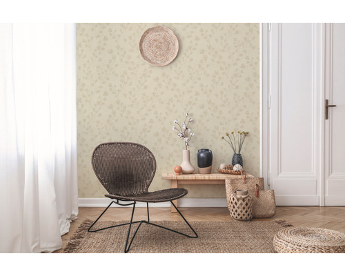 Vardagsrum med mönstrad tapet, flätad stol och dekorativa element för en mysig atmosfär.