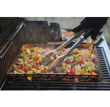 Grönsaker tillagade i en grillpanna på en grill, med grilltång