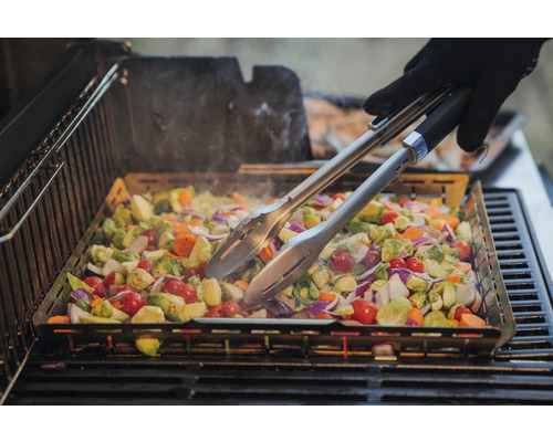 Grönsaker tillagade i en grillpanna på en grill, med grilltång