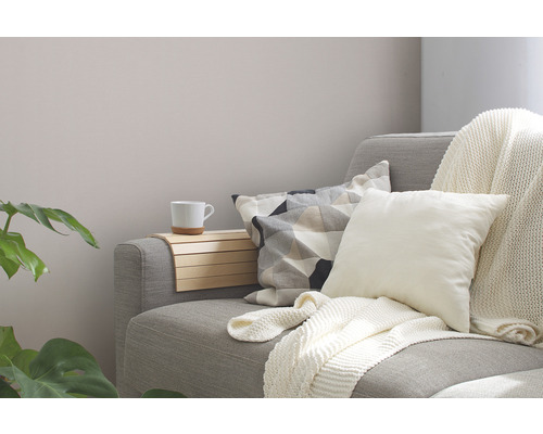 Mysig vardagsrumsscen med soffa, kuddar, filt och sidobord