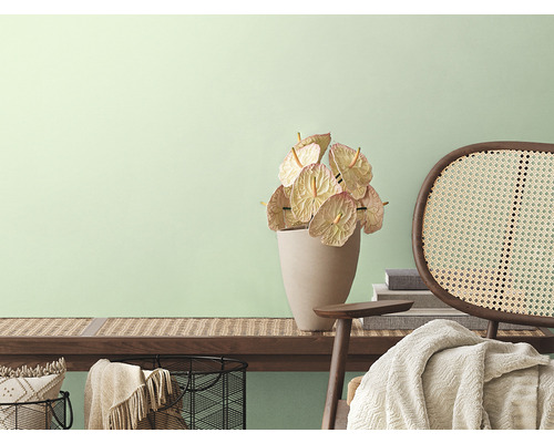 Dekorativt rum med träbänk, anthurium, rottingfåtölj och heminredning