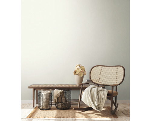 Vardagsrum med rottingfåtölj, träbänk, växter och dekoration på en matta