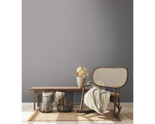 Vardagsrumsscen med träbänk, dekorationer, korgar och gungstol på en matta.