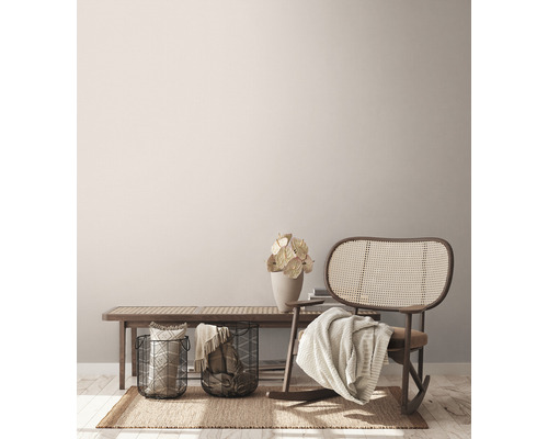 Vardagsrumsscen med bänk, gungstol i rotting, korgar och dekoration på en matta.