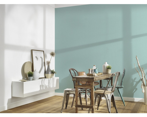 Matsal med träbord, stolar och vägghylla med dekorationer mot en färgad vägg