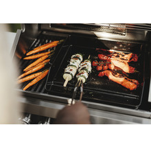 Grönsaker som morötter, zucchiniträffar och paprika på en grill.