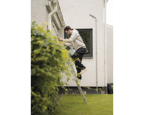 En person klättrar på en stege vid ett hus.