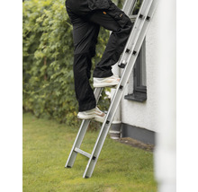 Person klättrar på en aluminiumstege framför ett hus.