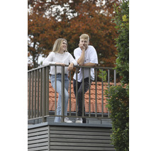 Två personer står på en balkong med metallräcke.