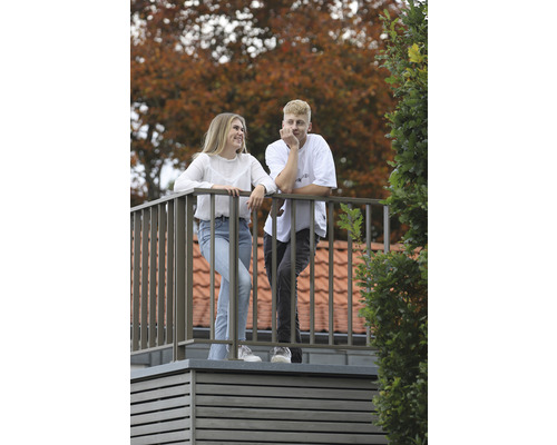 Två personer på en modern takterrass med metallräcke och träbeklädnad mot en höstlig bakgrund.