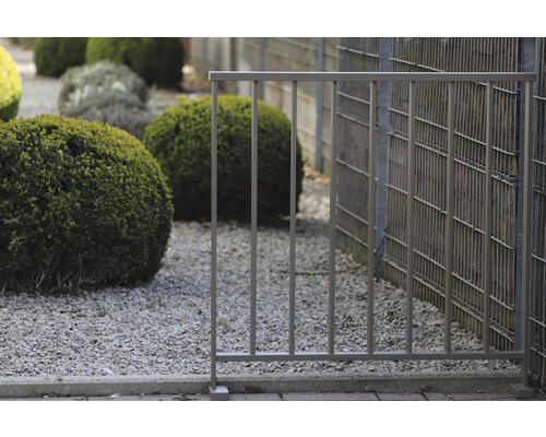 Metallstaket i trädgårdsområde med grus och buskar