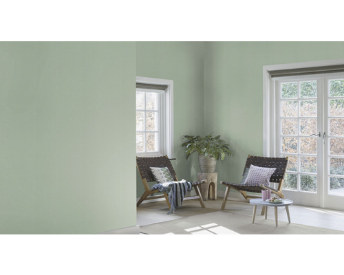 Ljust och vänligt rum med grön väggfärg, fåtöljer och dagsljus