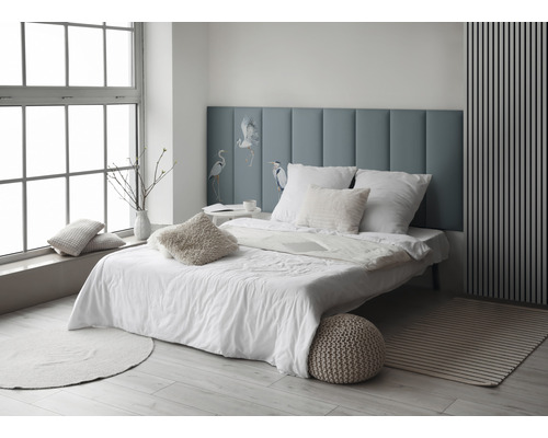 Ljust sovrum med säng, kuddar och blå sänggavel med fågelmotiv