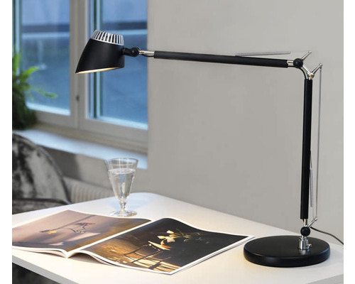 Skrivbord med justerbar skrivbordslampa och uppslagen bok