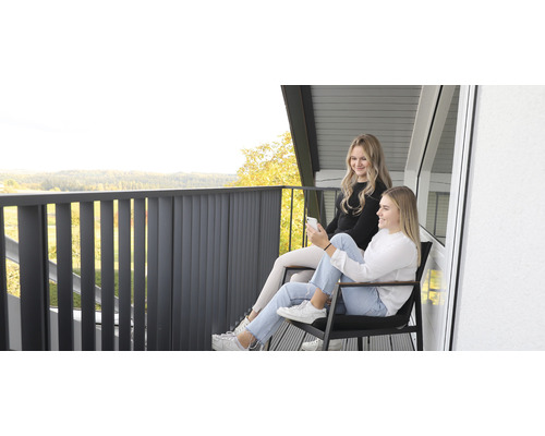 Två kvinnor sitter på en balkong med räcke och njuter av utsikten.