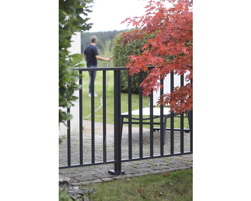 Trädgårdsscen med staket och en person som vattnar växter