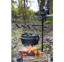 Gjutjärnspanna över öppen eld på ett stativ med campingbord och tillbehör utomhus