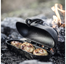 Öppen campinggrillpanna med tre potatisar vid en lägereld.