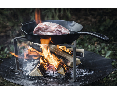 Kött i stekpanna över öppen eld på eldstad