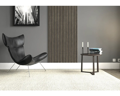 Vardagsrum med fåtölj, sidobord, väggpanel och en inramad bild.