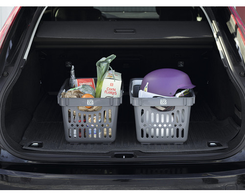 Två gråa shoppingkorgar i bagageutrymmet på en bil, fyllda med matvaror och en hjälm