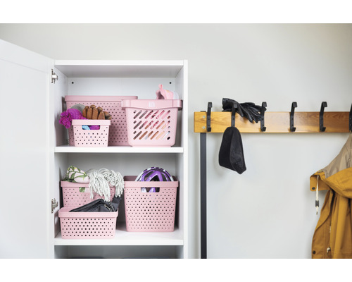 Hylla med flera rosa förvaringskorgar och klädhängare med mössa, handskar och jacka