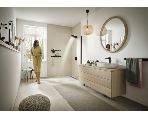 Ljust badrum med dusch, tvättställ och rund spegel