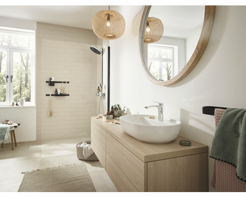 Ljust badrum med handfat, spegel, dusch och dekorationer