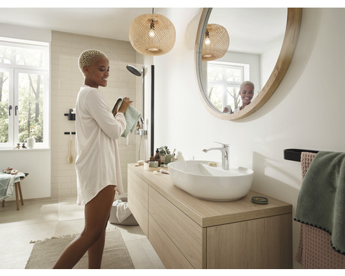 Modernt badrum med tvättställ, rund spegel och naturlig belysning