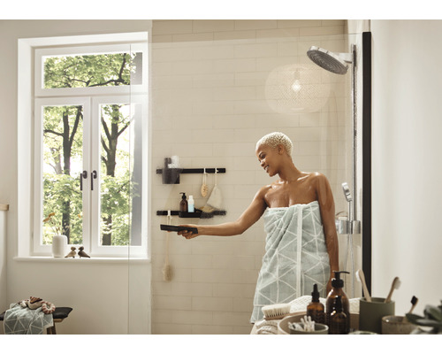 Ljust badrum med dusch, fönster och kvinna som rengör en duschvägg i glas med en skrapa