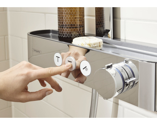 Närbild av en hand som trycker på en knapp på en duschblandare med hylla