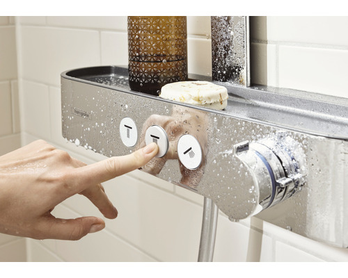 Duscharmatur med förvaringsutrymme i badrummet, en hand manövrerar knapparna