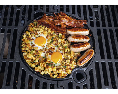Grillad frukost med ägg, bacon, korv och stekt potatis på en grillplatta