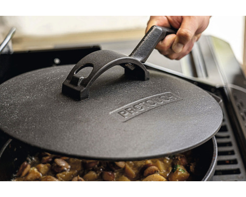 Gjutjärnslock på en kastrull med mat, hållen av en hand