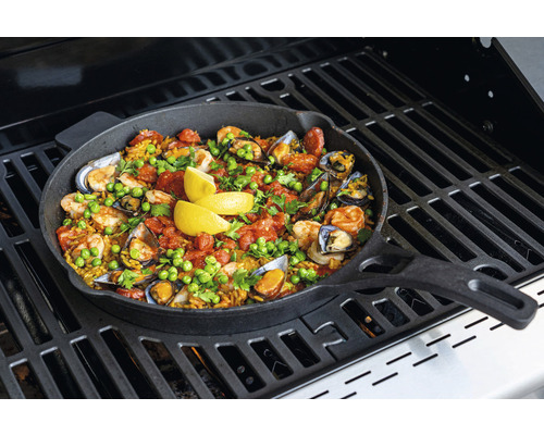 Paella tillagas i en stekpanna på en grill.